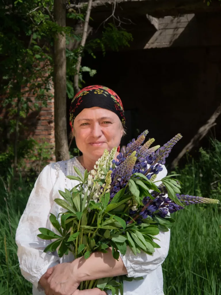 50-letnia kobieta w stylizacji wiejskiej, trzymająca kwiaty - artystyczne ujęcie przez BartiK.