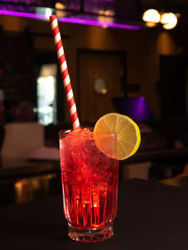 Zimny czerwony koktajl z cytryną i słomką - artystyczne ujęcie z sesji śniadaniowej w Restauracji Moxy.